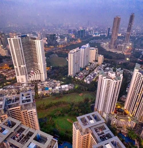 Aerial view of residential towers around a green park in a city at dusk